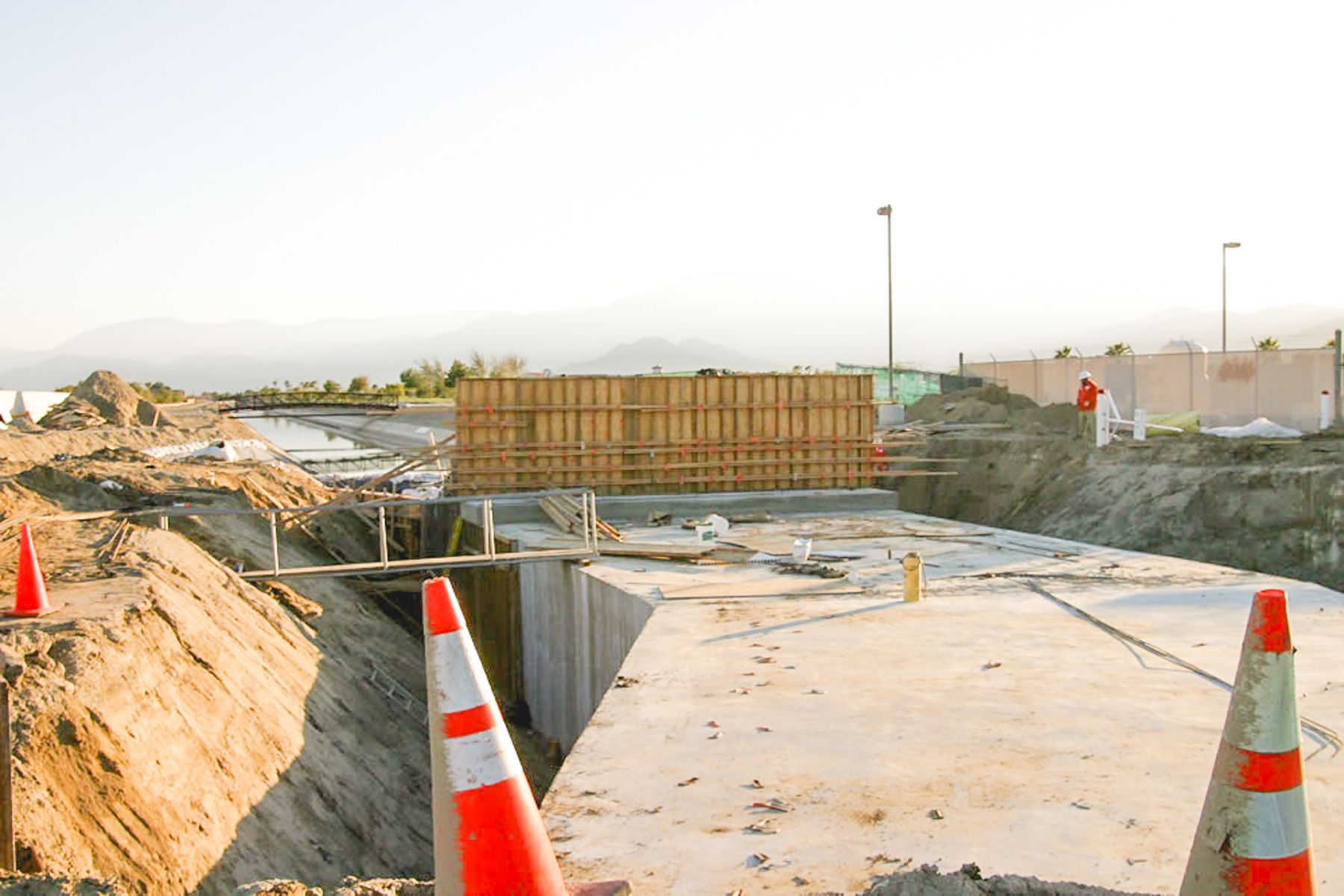 Poured concrete top slab spanning the excavation, traffic cones in the foreground and a formed wall at the far end