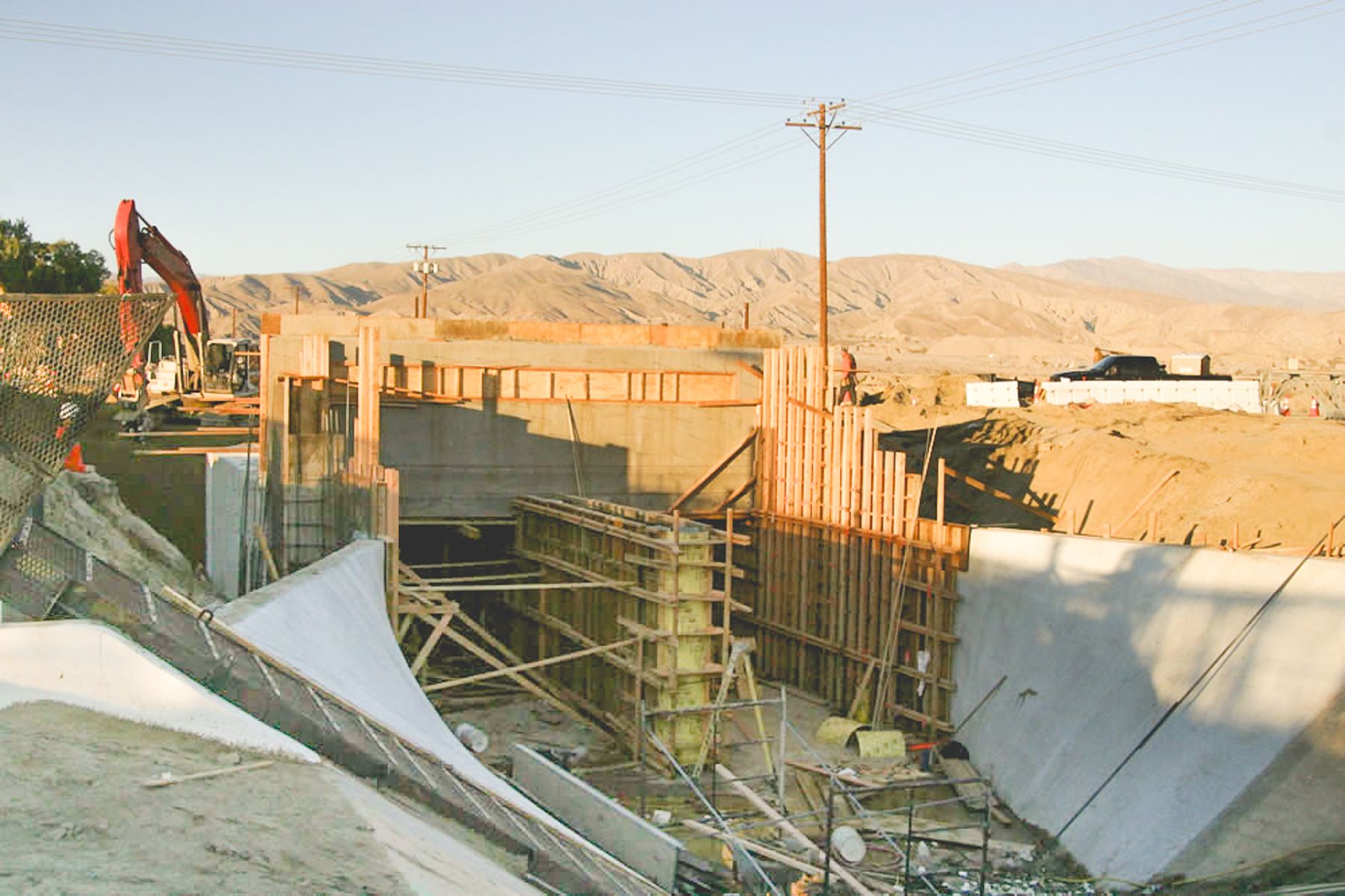 Wide view of the structure's formwork, vertical lagging and diagonal braces, with a curved white-coated transition in the foreground