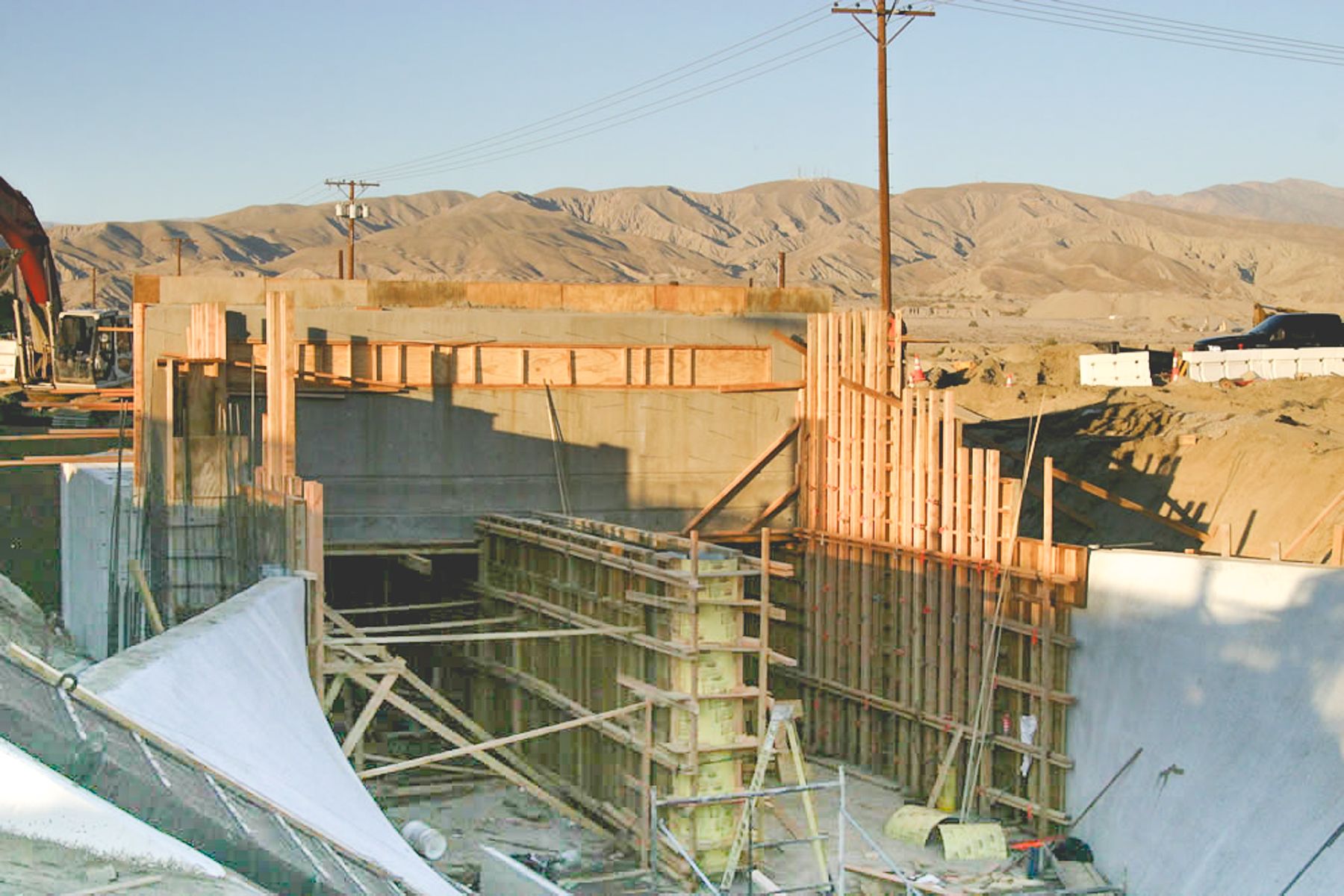 Timber-and-plywood forms and round column forms inside the structure's opening, with finished gray walls above