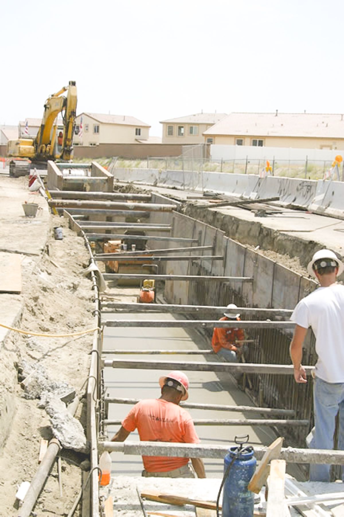 Crew members in hard hats working between cross-struts inside the narrow shored trench